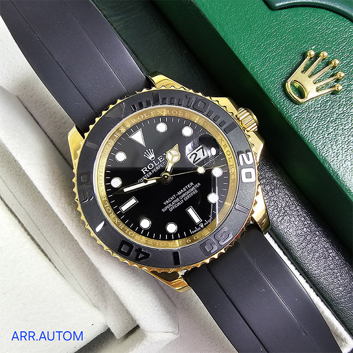 Rolex Yacht-Master con bisel negro y detalles en oro, caja de acero inoxidable, correa de goma negra. Un reloj de lujo, perfecto para cualquier ocasión.